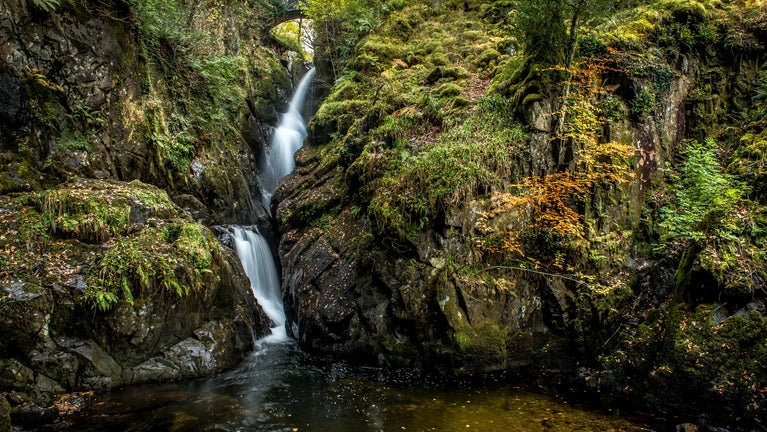 Waterfall cascading between green mossy rocks.